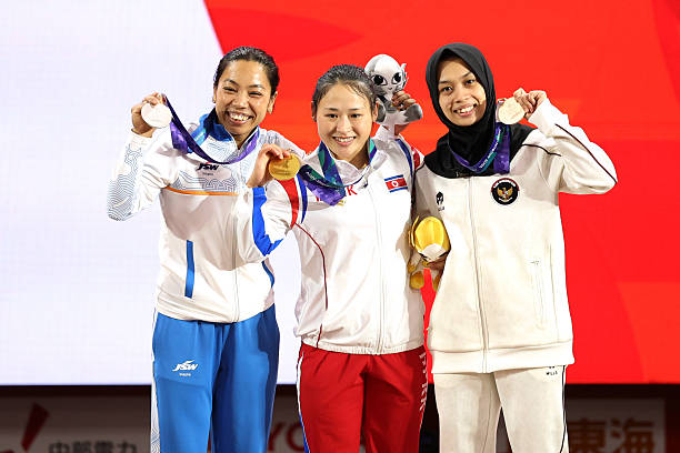 Gold medalist Song Gum Ri (C) of North Korea, silver medalist Mirabai Chanu Saikhom (L) of India and bronze medalist Luluk Diana Tri Wijayana (R) of Indonesia pose on the podium at the medal ceremony for the Weightlifting Women's 49kg on day four of the 20th Asian Games Aichi-Nagoya